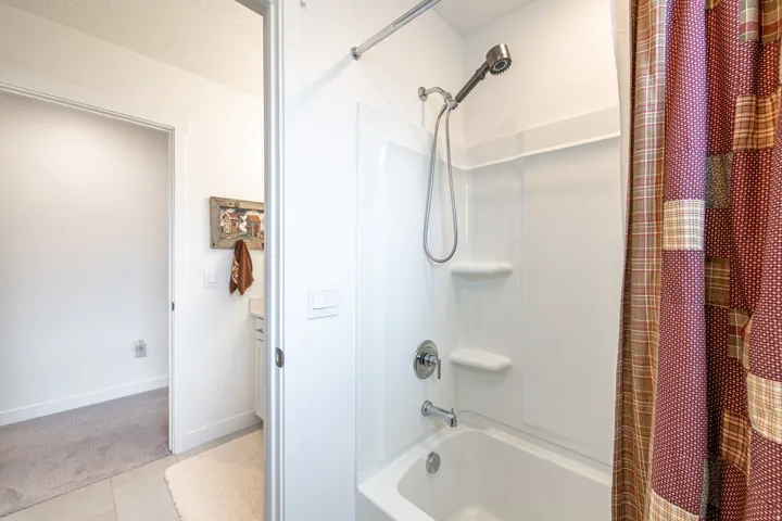 White tub/shower combination with a chrome shower head and built-in shelving