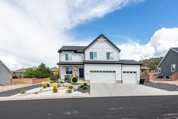 Modern farmhouse-style exterior with white vertical siding, black asphalt shingle roofing, and an integrated three-car garage