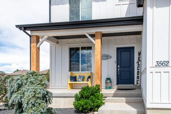 Board and batten exterior with a covered entry, wood-finish support columns, a dark-toned entry door, and concrete steps