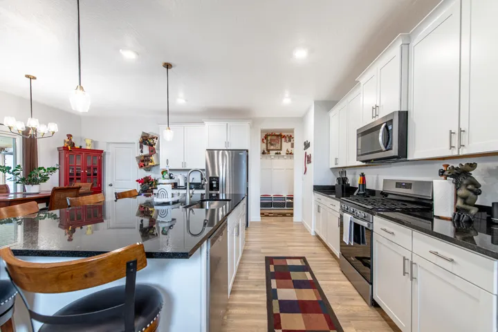 Kitchen featuring light wood-finish flooring, white cabinetry, dark countertops, a stainless steel gas range, and a stainless steel built-in microwave