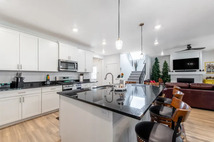 Modern kitchen featuring white cabinetry, dark countertops, a stainless steel microwave, and a kitchen island with seating