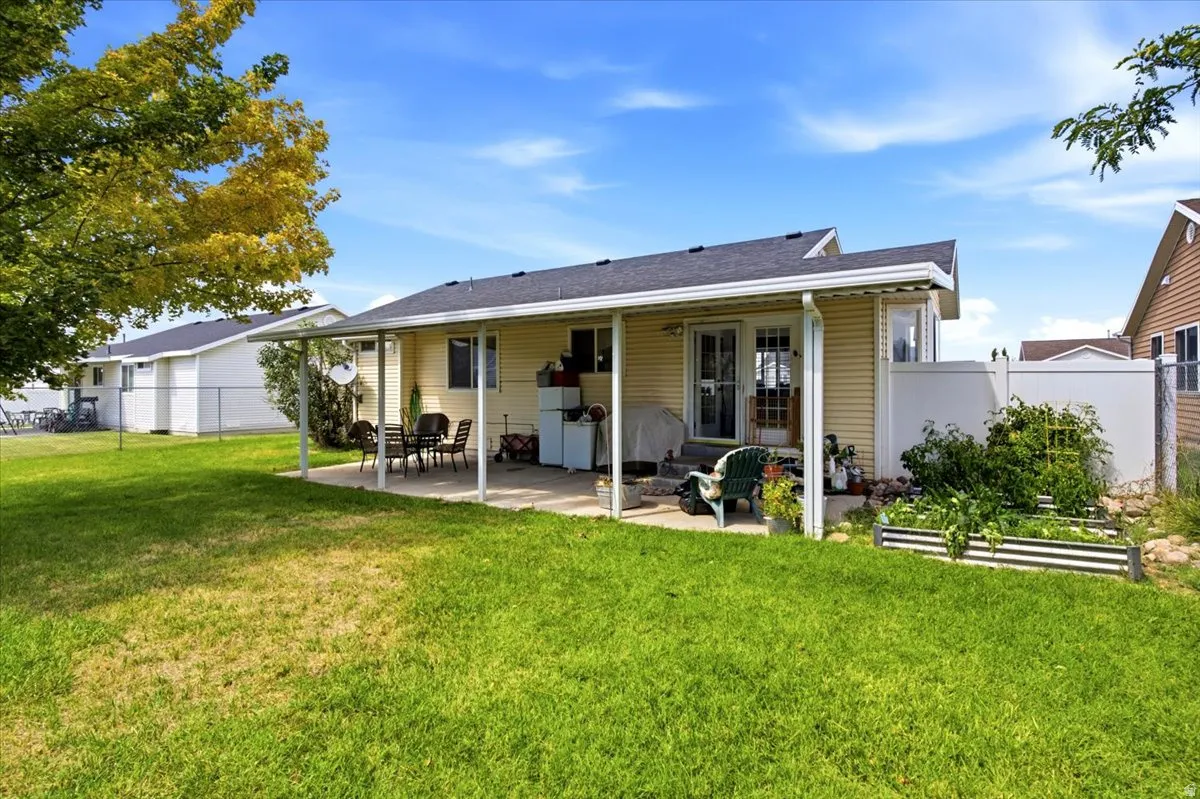 Expansive green lawn with a covered patio area and raised garden beds