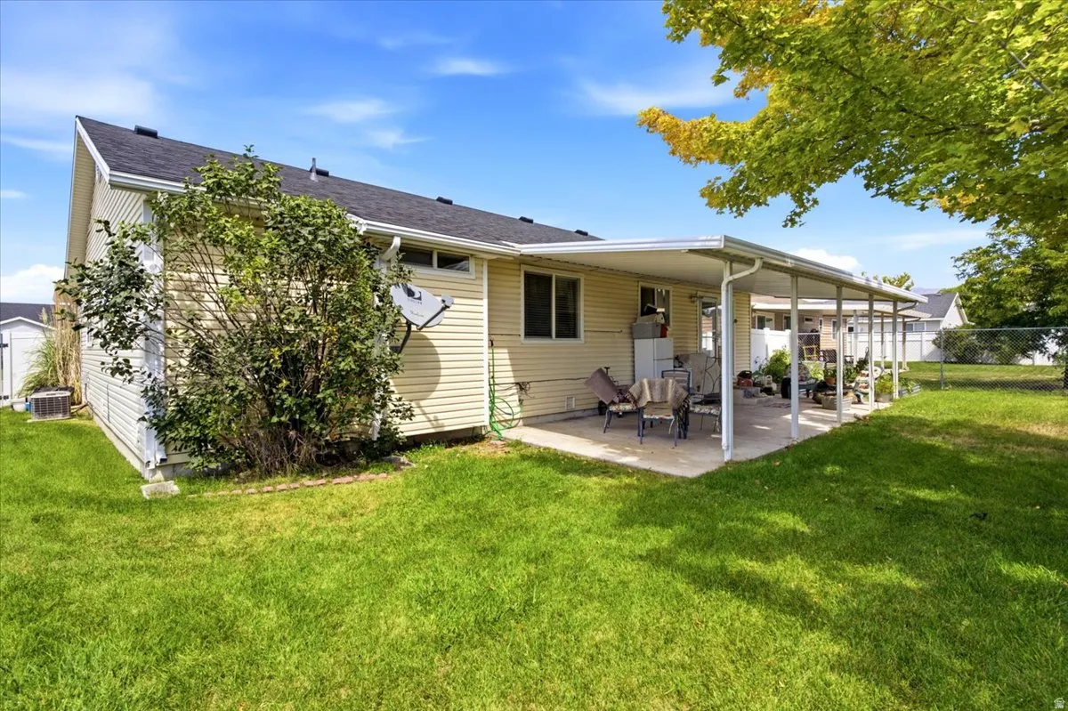 Expansive green lawn, covered patio, and mature trees creating shaded outdoor space