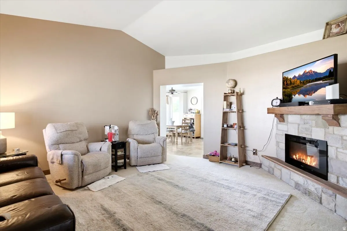 Vaulted ceiling in a spacious room, featuring a stone-clad fireplace with a wood mantle
