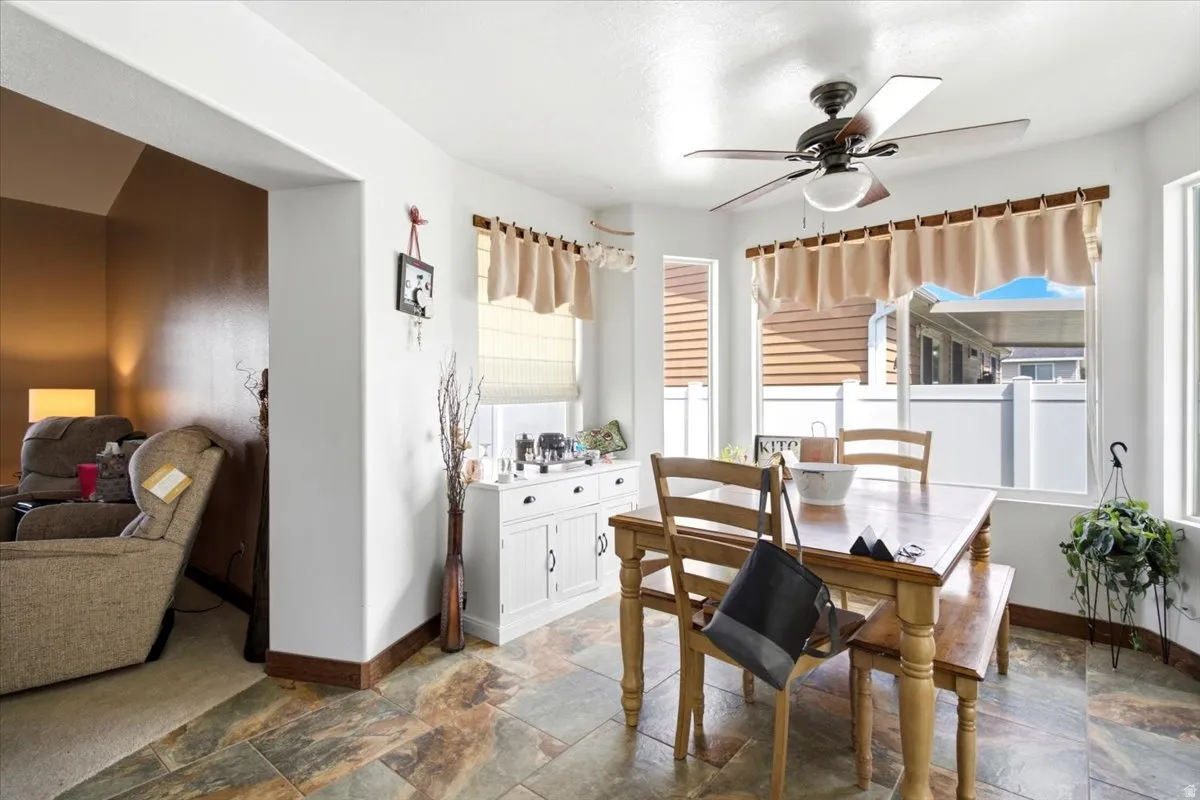 Bay window with natural light, ceiling fan, and multi-tone tile flooring