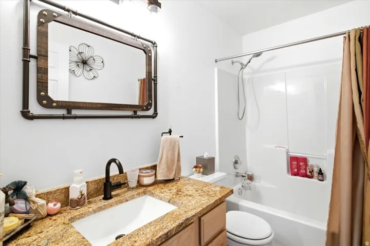 Vanity featuring a stone countertop, an undermount sink, and a matte black faucet