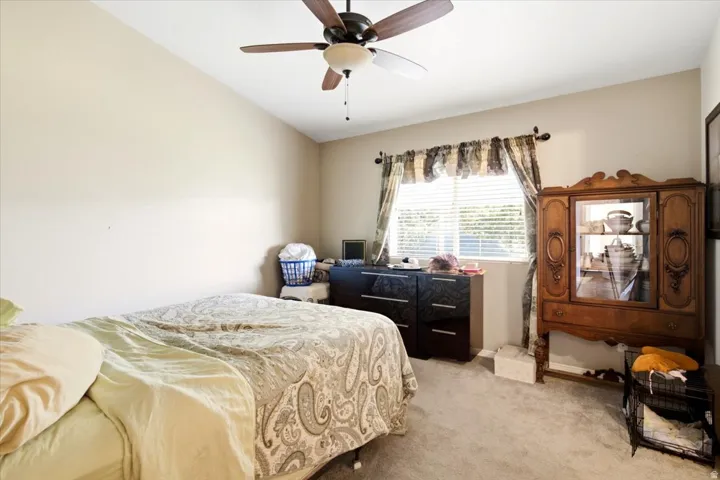 Vaulted ceiling with a ceiling fan, window with horizontal blinds, neutral wall paint, and carpeting