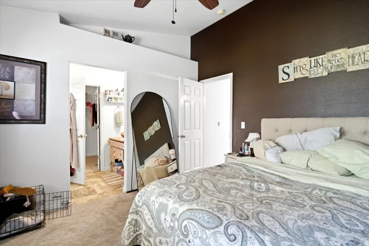 Vaulted ceiling with a ceiling fan, plush carpet, and two interior doors