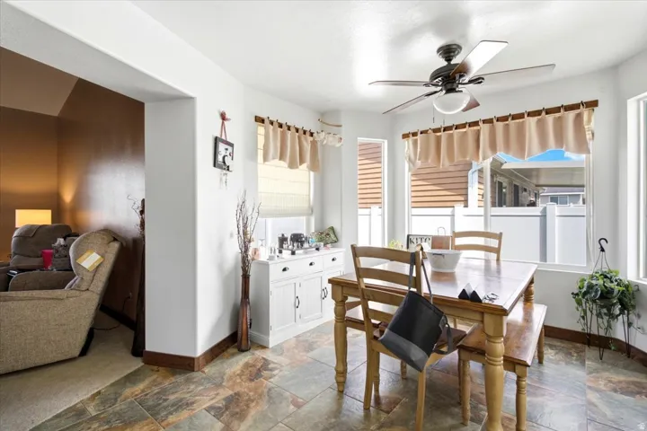 Bay window with natural light, ceiling fan, and multi-tone tile flooring