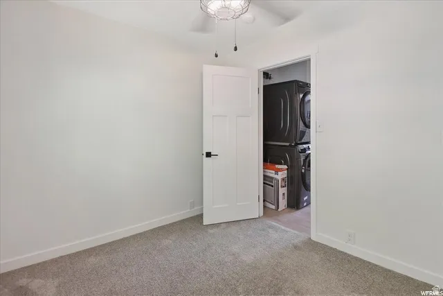 White walls, gray carpet, white trim, and a ceiling fan with integrated lighting
