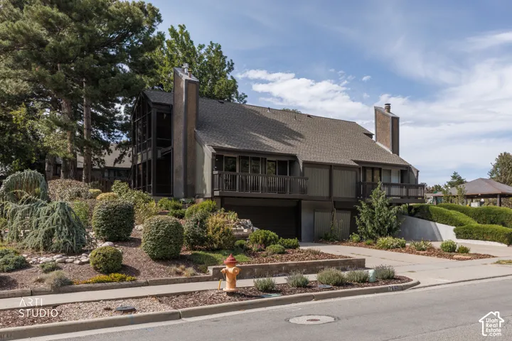 Contemporary exterior with a multi-level design, multiple balconies with wood railings, an attached garage, and prominent chimneys