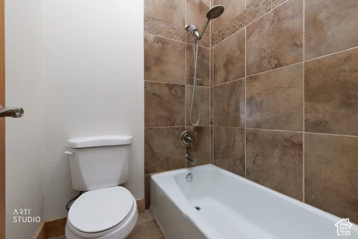 Tub and shower combination featuring a rainfall showerhead and handheld sprayer, surrounded by large format wall tile with a mosaic accent band