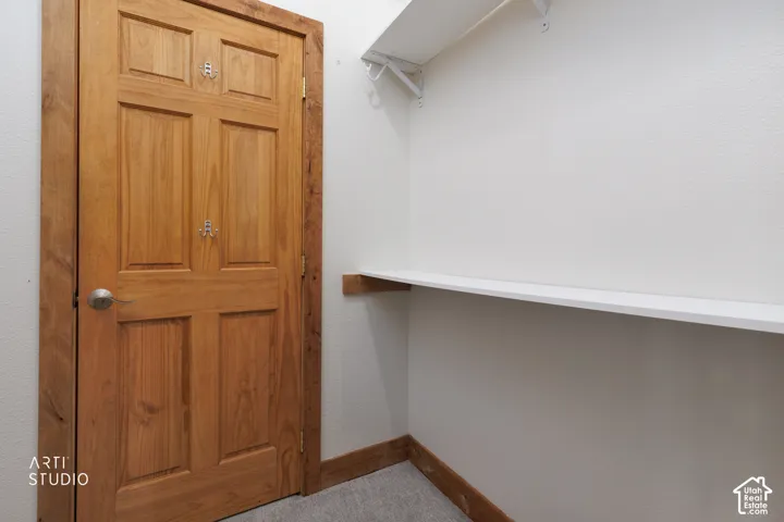 Recessed storage area with built-in shelving, wood-paneled door, and white painted walls