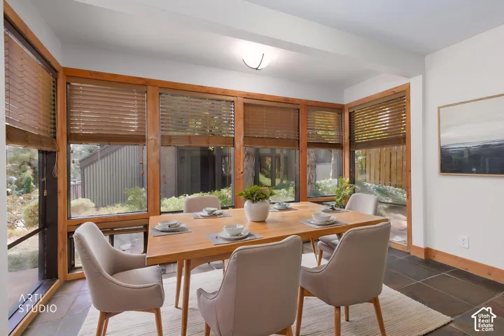 Sun-filled room featuring extensive natural wood-framed windows, wood-finish blinds, and dark-toned tile flooring
