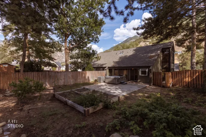 Expansive backyard featuring a concrete patio, raised garden beds, and mature trees