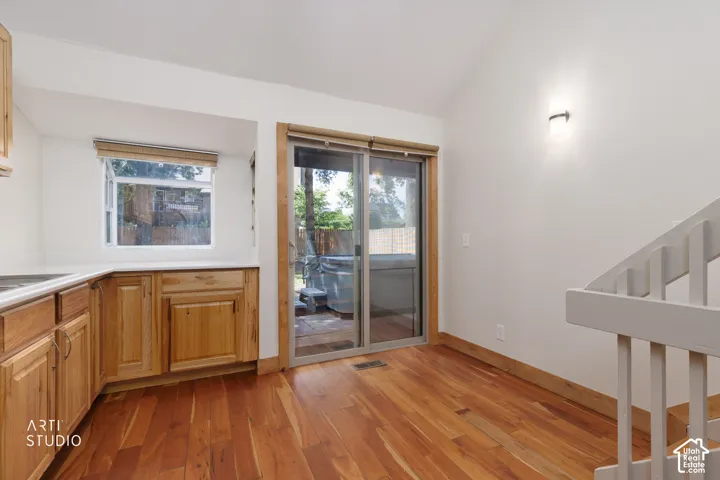 Wood-finish flooring, light wood cabinetry, white countertops, built-in hot tub, and a sliding glass door