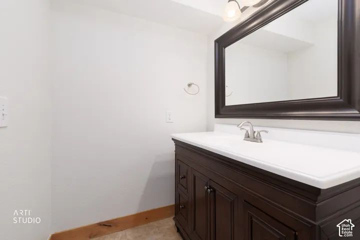 Dark wood-finish vanity with white countertop and integrated sink, framed mirror, and brushed nickel faucet