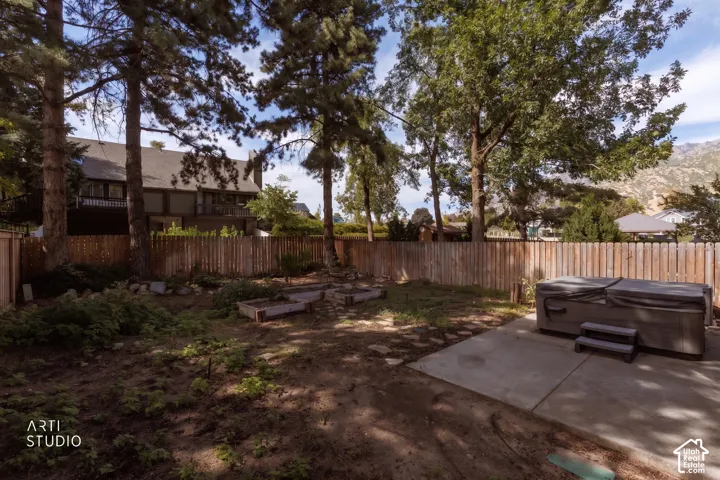 Private backyard featuring a hot tub, concrete patio, and raised garden beds