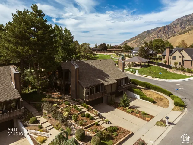 Multi-level residence featuring a prominent chimney, a tiered landscaped front yard, and a paved driveway leading to a garage