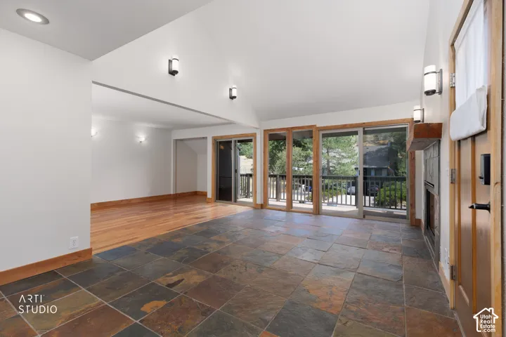 Vaulted ceilings, slate tile flooring, wood-finish flooring, built-in fireplace, and sliding glass doors with balcony access