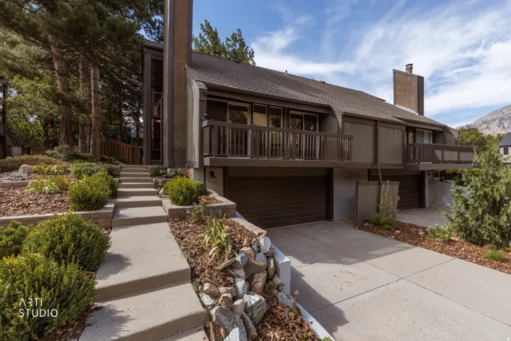 Terraced landscaping with established plantings and concrete steps leading to the entrance