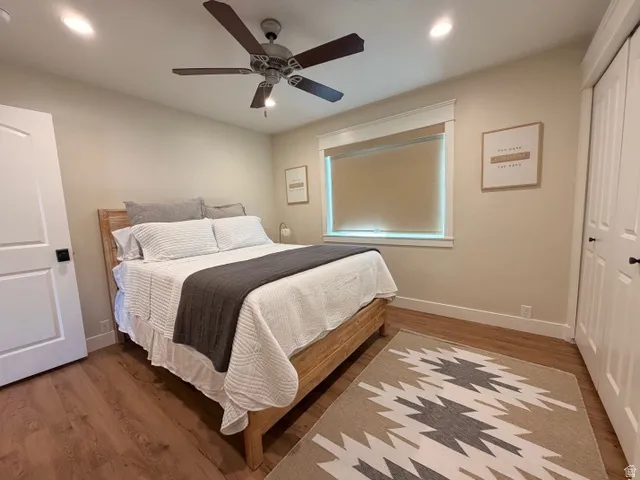 Wood-finish flooring, ceiling fan with integrated lighting, recessed lighting, window with roller shade, and bi-fold closet doors