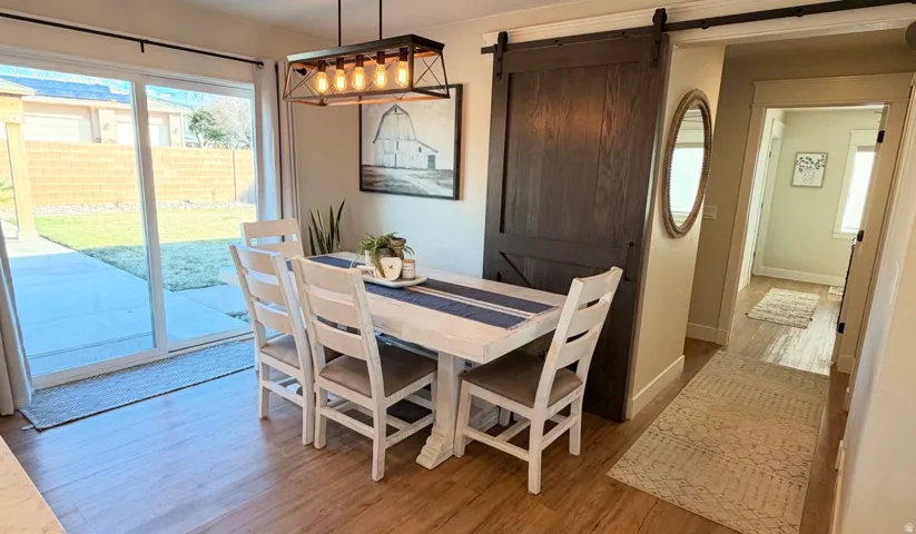 Wood-finish flooring throughout, sliding glass door with backyard access, and a dark wood barn door