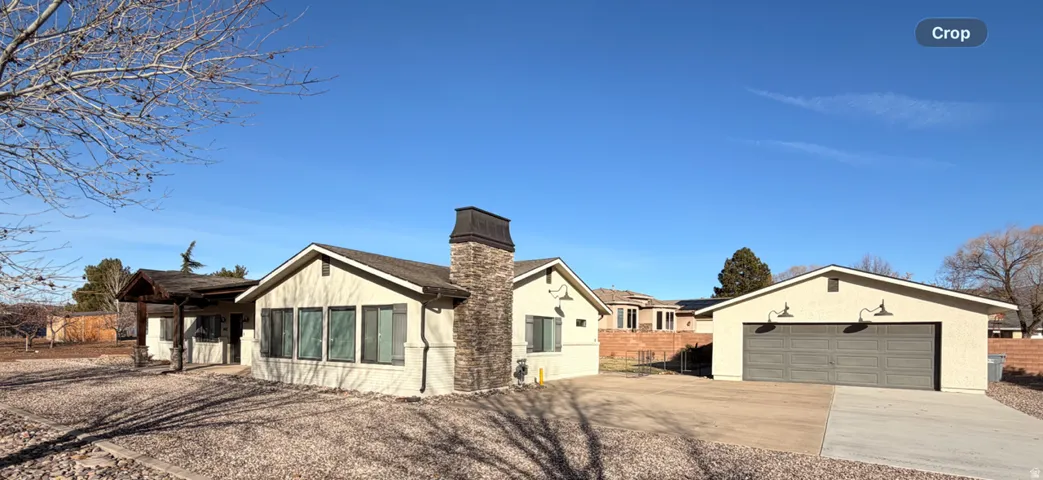 Stucco exterior with a prominent stone-clad chimney and a multi-panel garage door