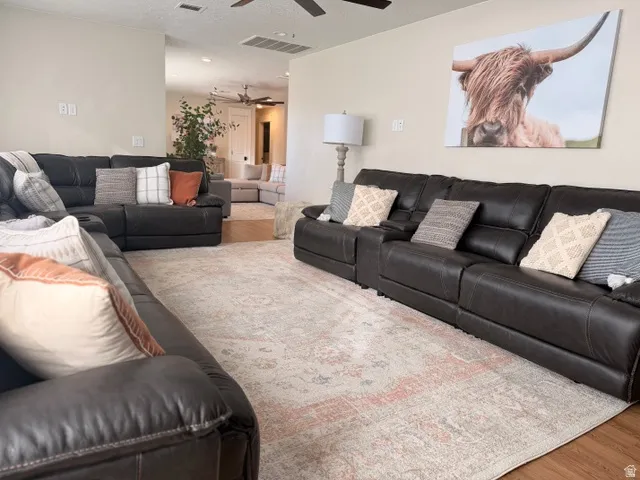 Recessed ceiling lighting, ceiling fans, light-toned wall paint, wood-finish flooring, and open-concept design