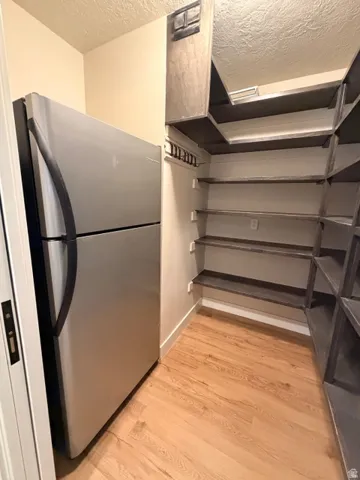 Built-in shelving, stainless steel refrigerator, and wood-finish flooring