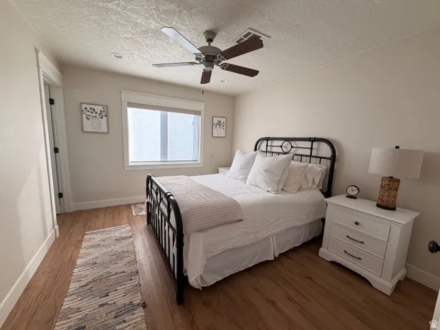 Wood-finish flooring, ceiling fan with integrated lighting, white trim and baseboards, and a window with blinds
