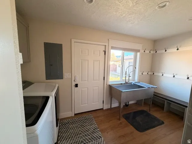 Dedicated utility space featuring a stainless steel utility sink, wood-finish flooring, and built-in coat hooks