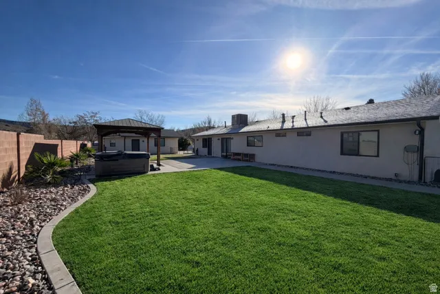 Expansive lawn area with concrete curbing, a covered gazebo, and a hardscaped perimeter