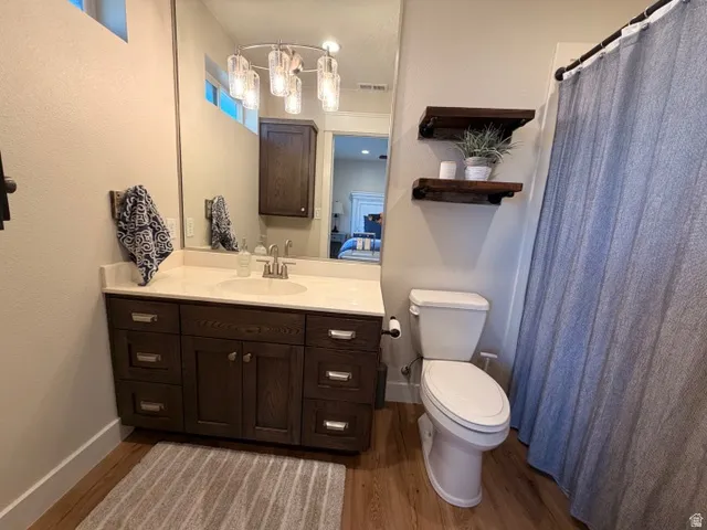 Dark wood-finish vanity with a light-toned countertop, under-mount sink, and dual-handle faucet