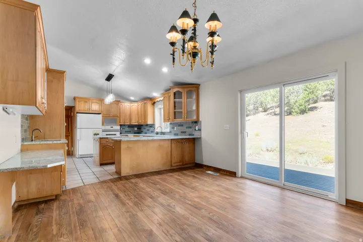 Kitchen featuring wood-finish flooring, light wood cabinetry, light-toned countertops, and a tile backsplash
