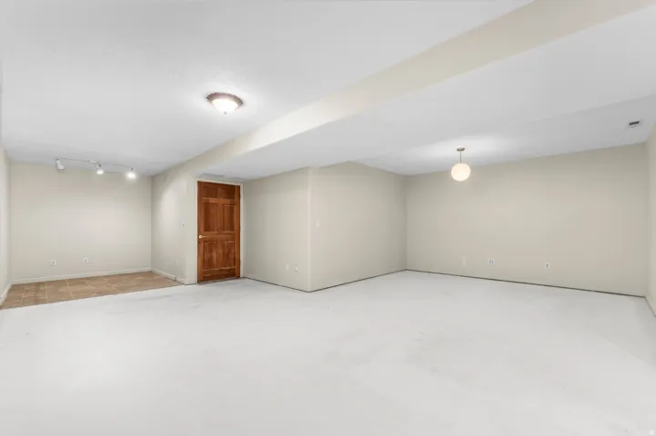 Expansive room featuring light-colored carpeting, a separate tiled area, recessed lighting, and a solid wood door