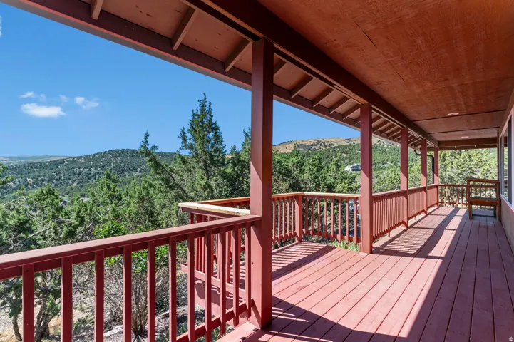 Expansive outdoor deck with a red-stained wood finish, full-length railings, and a covered ceiling