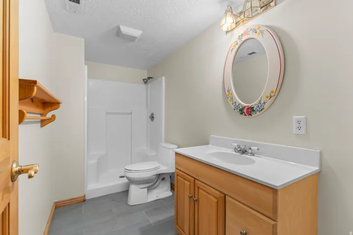 Full bathroom featuring a single-sink vanity with wood cabinetry, a white countertop, a shower-tub combination, and gray tile flooring