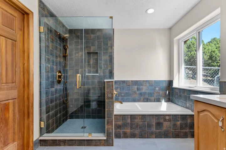 Glass-enclosed shower with dark-toned tile surround and built-in niche