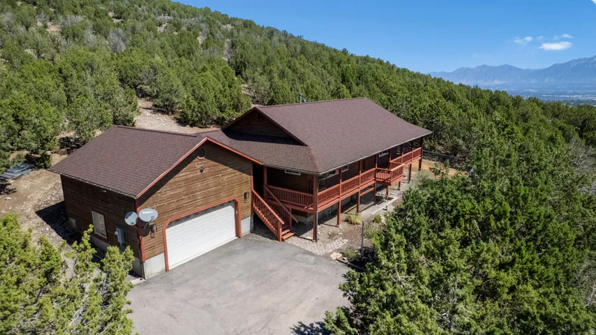 Wood-sided exterior with a two-car garage, expansive wrap-around deck, and a multi-level roofline