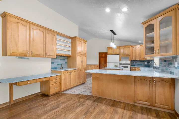 Spacious kitchen featuring light wood cabinetry, light-toned countertops, and a blue subway tile backsplash