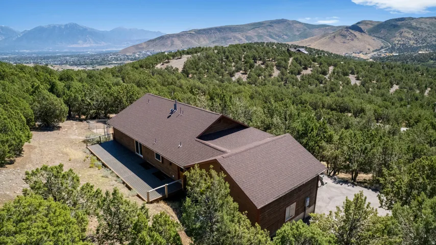 Wood-sided residence with an expansive deck, asphalt shingle roof, and a gravel driveway