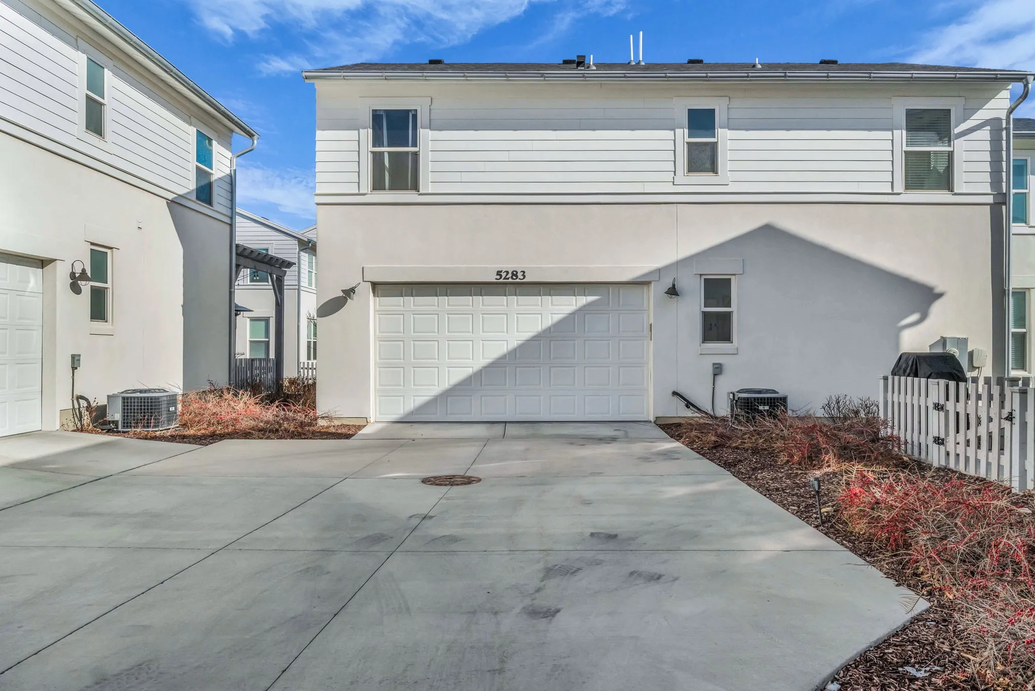 Attached garage with a panel door, concrete driveway, and stucco and horizontal siding exterior