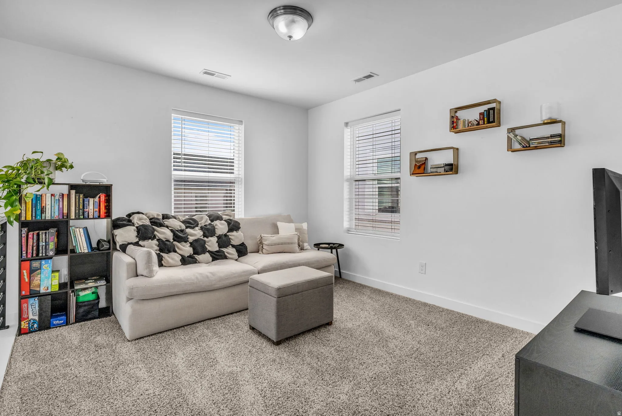 Recessed lighting and ceiling-mounted light fixture illuminate a carpeted room with multiple windows