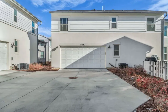 Attached garage with a panel door, concrete driveway, and stucco and horizontal siding exterior