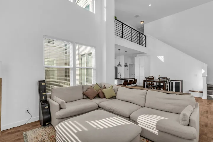 Open-concept interior featuring high ceilings, wood-finish flooring, and a modern kitchen with pendant lighting