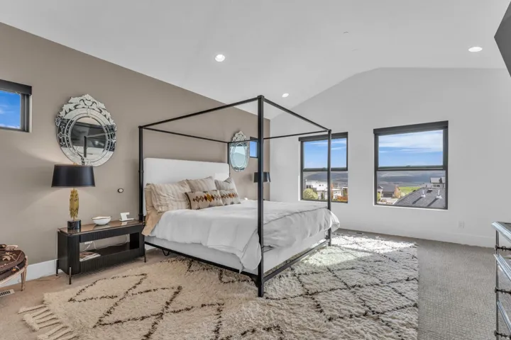 Vaulted ceiling with recessed lighting, multiple windows, and neutral wall tones