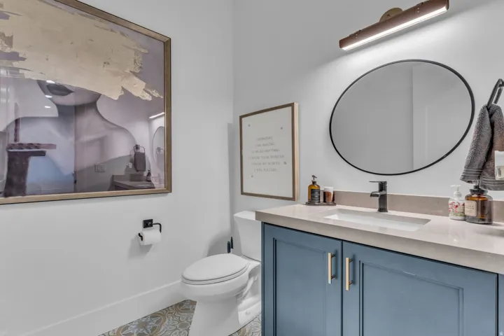 Modern vanity featuring a blue base cabinet with gold-toned hardware, an integrated rectangular sink, and a light-toned countertop