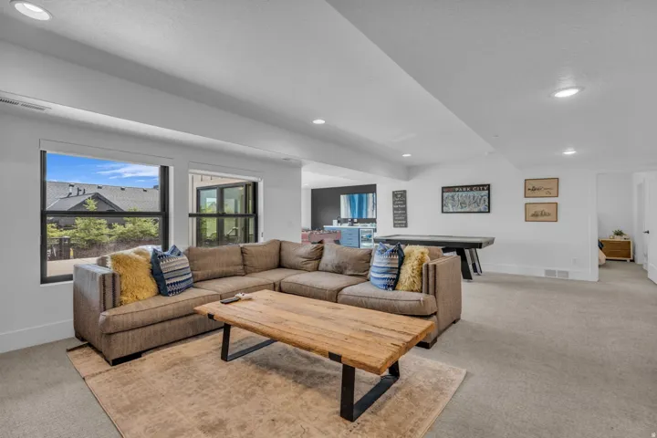 Spacious living area featuring carpet flooring, recessed lighting, and large windows with black frames
