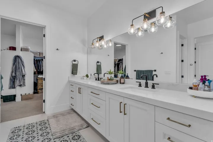 Dual vanity with white cabinetry, gold-finish hardware, and a light-toned countertop